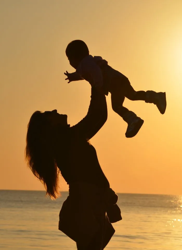 Woman joyfully lifting her baby, representing life insurance protection